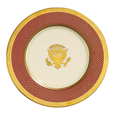 Cream porcelain plate with a red latticed border, gold rim, and a central Presidential Seal.