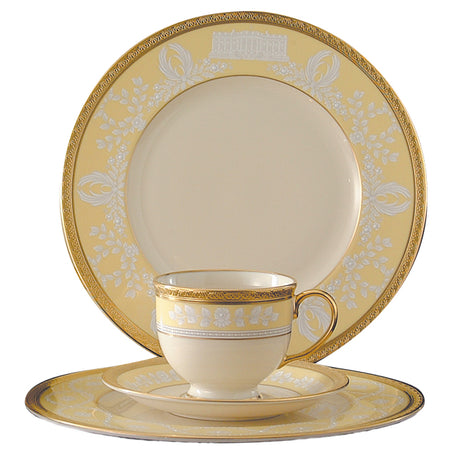 Cream dinnerware set with yellow borders, white floral motifs, and gold rims.