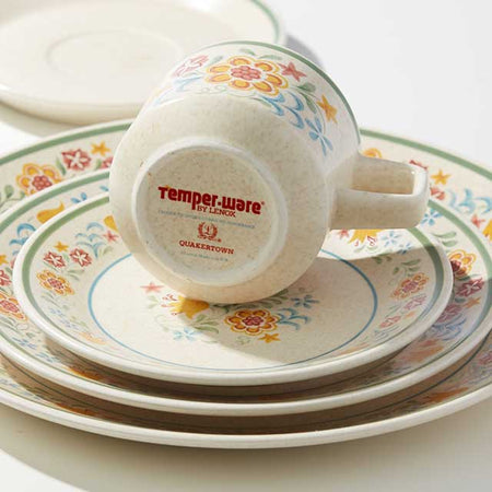 Ceramic dinnerware set with colorful floral patterns and a "Temper-ware by Lenox" stamp on the bottom of a teacup.