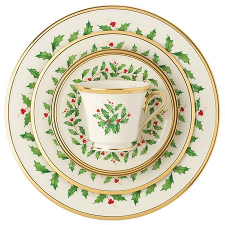Cream dinnerware set featuring green holly leaves, red berries, and gold rims.