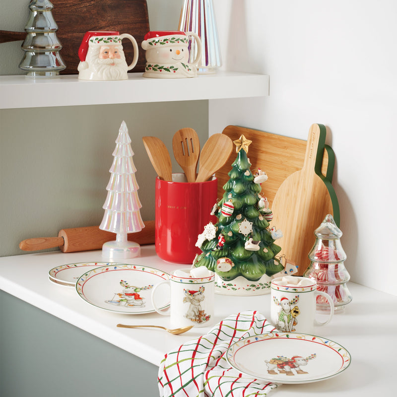 Decorative Christmas kitchen scene with mugs, plates, and a tree on a countertop.