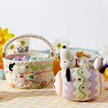 Snoopy-themed Easter basket and cookie jar on a checkered tablecloth with flowers in the background.