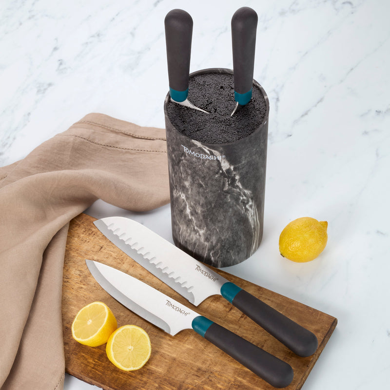 Kitchen knives with black handles and knife block on a wooden board with lemons.
