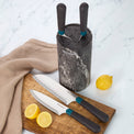 Kitchen knives with black handles and knife block on a wooden board with lemons.