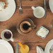 Wooden table set with waffles, coffee, whipped cream, and orange juice.